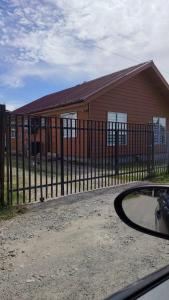 a house with a fence in front of a building at MyE in Frutillar