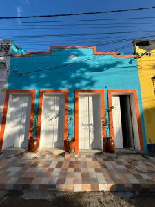 een blauw gebouw met witte deuren en planten erop bij Pousada e Restaurante Morena Raiz in Olinda