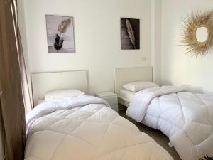 2 bedden in een witte kamer met een spiegel bij Madinaty Comfort Residence in Madinaty