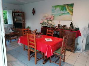 a dining room with a red table and chairs at Les Orchidées - classé 3 étoiles -Plage à 5 mn in Sainte-Anne