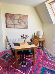 a dining room with a table and chairs on a rug at Four Seasons B&B, Ground floor room, private bathroom, 3rd floor loft living area & self serve continental breakfast in Pitlochry