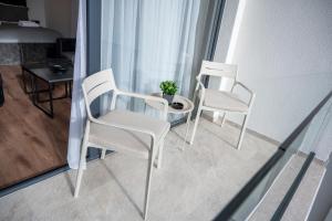 two white chairs and a table with a potted plant at Felicita Deluxe Apartments with Free Parking in Sarajevo