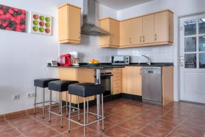 a kitchen with wooden cabinets and bar stools at Villa Mariña- Heated pool in Playa Blanca