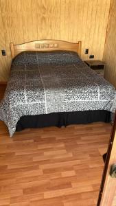een bed in een kamer met een houten vloer bij cabañas walls 3 in Pucón
