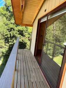 een houten veranda met een glazen schuifdeur op een huis bij cabañas walls 3 in Pucón