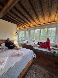 two people sitting on beds in a room with windows at Stupa Eco Vila in Barra de Ibiraquera