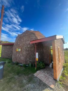 a small brick house with a dog sitting outside at Domo Kuram in Ancud +8 photos