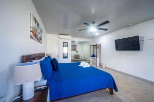 a bedroom with a blue bed and a ceiling fan at Ozeano Hotel & Surf Bar in Jacó
