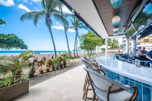 a bar on the beach with palm trees and the ocean at Ozeano Hotel & Surf Bar in Jacó