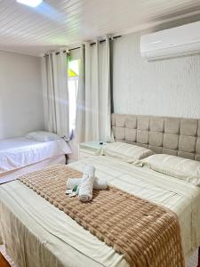 a bedroom with two beds with a stuffed animal on the bed at Suite em Hospedagem 100m da BR! in São José
