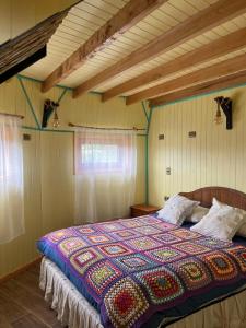 a bedroom with a bed with a colorful quilt on it at Domo Kuram in Ancud