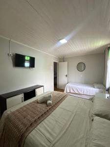 a bedroom with two beds and a flat screen tv at Suite em Hospedagem 100m da BR! in São José +10 photos
