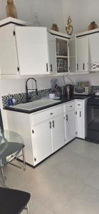 a kitchen with white cabinets and a sink at Martha's House Kia in Soufrière