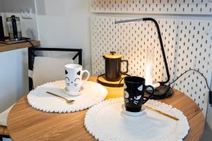 a wooden table with two cups and plates on it at Silverka Studio in Tarnowskie Góry