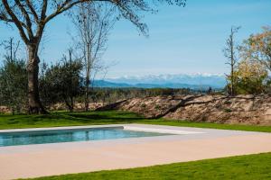 a swimming pool in a field with mountains in the background at Hotel Mas Vidal Vilafreser in Vilademuls