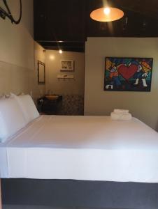 a large white bed in a room with a painting on the wall at Studio Gamboa in Garopaba +38 photos