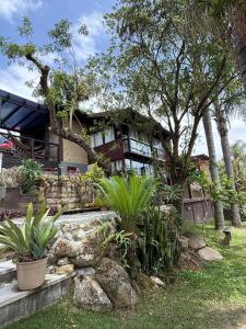 a house with trees and plants in front of it at Studio Gamboa in Garopaba
