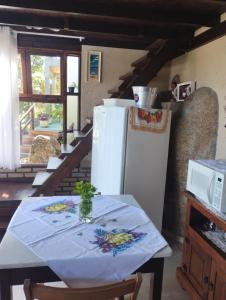 a kitchen with a table and a white refrigerator at Studio Gamboa in Garopaba