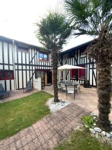 a courtyard with two palm trees in front of a building at Maison de Nathony in Maisons-en-Champagne