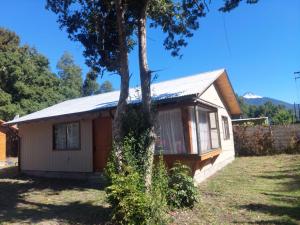 a small house with a tree in front of it at cabañas walls 2 in Pucón