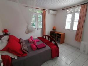 a bedroom with a bed with red pillows on it at Les Orchidées - classé 3 étoiles -Plage à 5 mn in Sainte-Anne