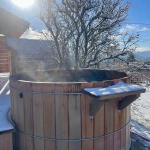 a hot tub with snow on top of it at Cocon d'hiver dans le Jura - Option spa - Gîte cosy chez Ô JurassiK in Cuttura