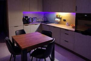 a kitchen with a wooden table and some purple lights at Apartament Corner Cappuccino z wanną z hydromasażem w centrum Tomaszowa! Parliamo anche Italiano! in Tomaszów Mazowiecki