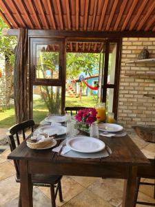 a wooden table with plates and flowers on it at Pousada Ventoria in Canguaretama +33 photos