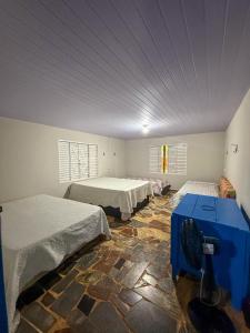 a room with two beds and a blue table in it at Casa aconchegante e tranquila in Chapada dos Guimarães