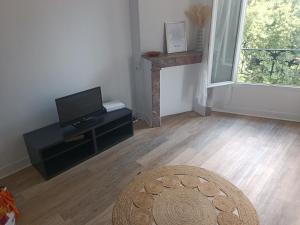 a living room with a flat screen tv and a table at T2 Cosy 20 min Paris in Bezons