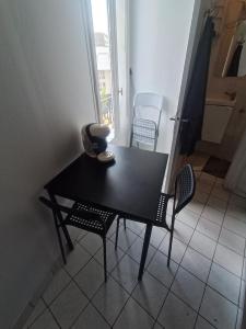 a black table and chairs in a room with a window at T2 Cosy 20 min Paris in Bezons