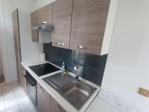 a kitchen with a sink and wooden cabinets at T2 Cosy 20 min Paris in Bezons