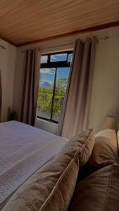 a bedroom with a bed and a large window at Arenal Stone House in Ángeles