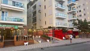 a person standing on a sidewalk in front of a building at Shengjin apartaments kozmai in Shëngjin