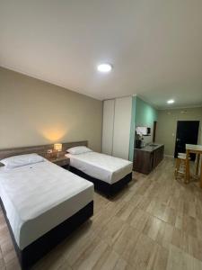 a hotel room with two beds and a desk at Apart Altos Del Pilar in Pilar