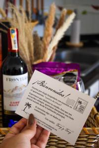 a person holding a piece of paper with a bottle of wine at Apto Diners Rodadero WiFi - Piscina - Playa in Rodadero