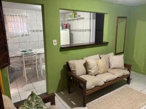 a green room with a couch and a mirror at Jully''s house in Arraial do Cabo