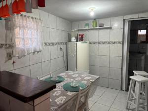 a small kitchen with a table and a refrigerator at Jully''s house in Arraial do Cabo