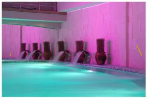 Una habitación con una piscina con paredes rosas y un grupo de pinceles. en SunStone Apartment, en Zlatibor