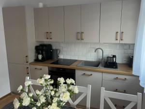 a kitchen with white cabinets and a vase of flowers at Odskocznia2 in Maniowy +7 photos