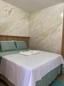 a bed with white sheets and blue pillows on it at Flat Sétima Arte in Cairu