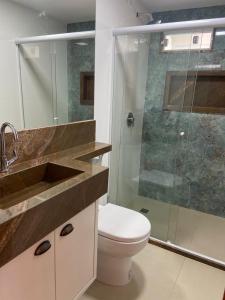 a bathroom with a toilet and a glass shower at Flat Sétima Arte in Cairu