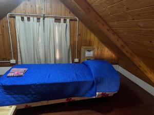 a bedroom with a blue bed in a attic at Cabaña, Sol y Paz in Lima