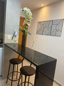 a black counter with two stools and a vase with flowers at Park Cowboy - Valentina in João Pessoa