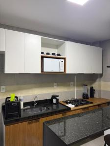 a kitchen with white cabinets and a sink and a microwave at Park Cowboy - Valentina in João Pessoa