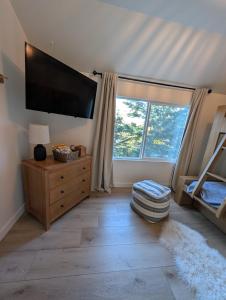a bedroom with a flat screen tv and a large window at Yama Cabin - 5 min walk to the village, EV plug, hot tub, kid & pet friendly in Lake Arrowhead +22 photos