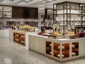 een restaurant met een buffet met eten dat wordt tentoongesteld bij Fairmont Wuhan in Wuhan