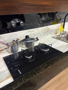 a stove top with pots and pans on top of it at In concept chalé completo in Duque de Caxias
