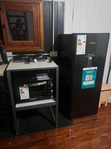 a microwave oven next to a black refrigerator at Cabaña, Sol y Paz in Lima