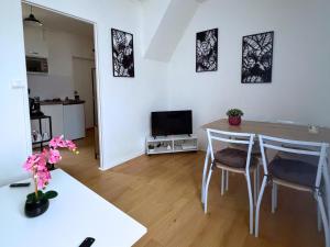 een woonkamer met een tafel, stoelen en een televisie bij L'échappée belle pour 5 in Saint-Quentin
